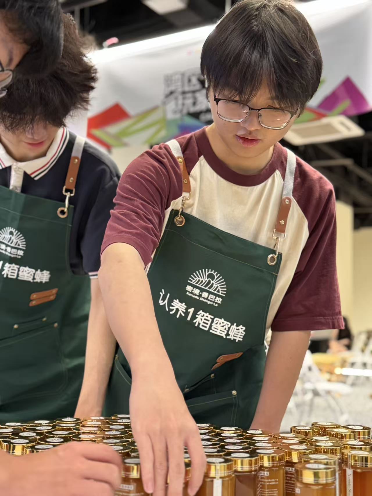 Two volunteers laying out rows of honey jars on the booth table