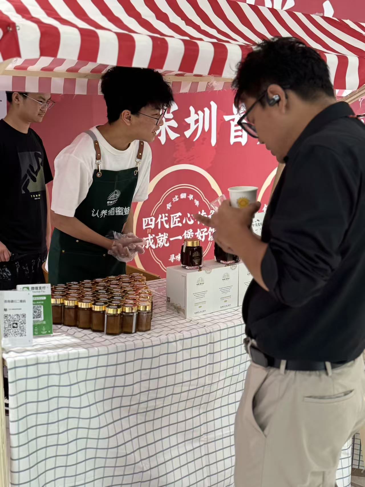 Student volunteer talking with a customer at an outdoor charity-sale stall